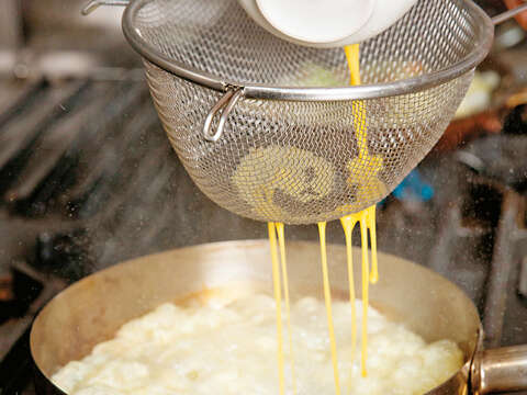 4.油加溫到190度，讓蛋液透過漏網倒入油鍋，炸成蛋酥。（攝影／林煒凱）