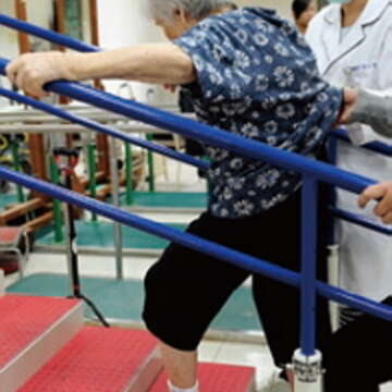 物理治療師協助葉婆婆練習正確不傷關節的爬樓梯方式。（郭鳳孝攝）