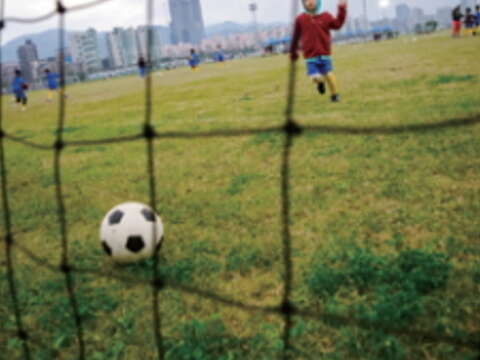 在迎風河濱公園的草地上奔跑、踢足球，與孩子一同創造回憶。（許斌攝）