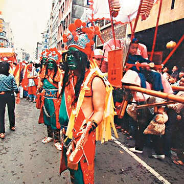 1980年代繞境時,八將團後面會跟著自行畫臉參與的八將腳,一旁還有以人力抬轎發送鹹光餅的隊伍。(圖/邱添財提供)