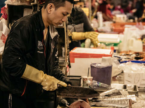 用專注的神情和熟練的刀法分切鮮魚，是魚市場的日常風景。