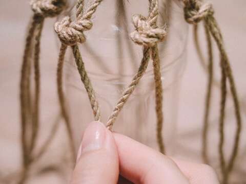 STEP 06 以一個繩結為一股，將相鄰兩股各取1條麻繩於適當長度處打結固定形成繩結，並重複前述步驟至完成第一層繩結；以第一層繩結為基準，用同樣方法層層往下編織。各層繩結之間的間距，會決定袋子的網洞大小。