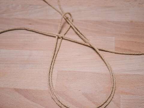 STEP 02 取1條麻繩作基繩，再取另1條麻繩對摺後，以對摺處置於基繩下方，並將另一頭的麻繩尾端部分繞過基繩後，套入繩圈並拉緊固定。