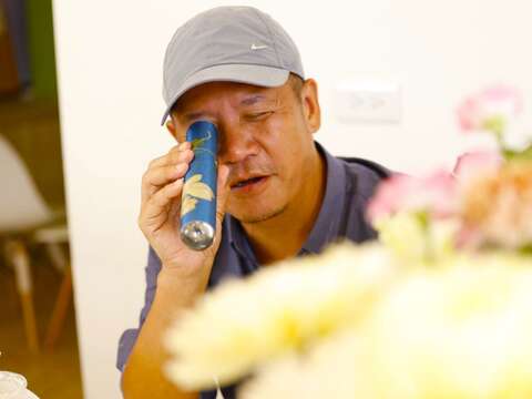 設計師蕭青陽拿起萬花筒，觀察萬花筒裡的花花世界