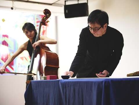 知名书法家暨诗人许悔之使用稻秆现场挥毫，并由国家交响乐团低音提琴手蔡歆婕(图左)伴奏。
