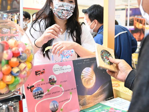 向現場民眾介紹臺北遊程QA問答，提供臺北特色推廣品。(圖片來源：臺北市政府觀光傳播局)
