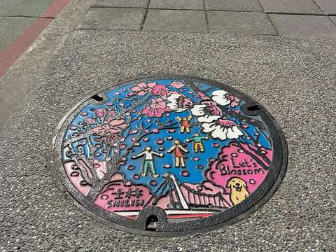 Painted manhole cover in Shilin District – Let’s Bloom Cherry Blossoms in Yangmingshan Created by Li Ming-Tao, Akibo Works