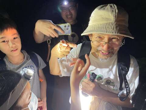 富陽公園蛙調志工郭水源老師在讓小朋友們輪流體驗蛙類吸盤的黏著力，接著示範如何將斑腿樹蛙裝入網袋，進行移除外來種的作業。(圖片來源：臺北市青少年發展暨家庭教育中心)