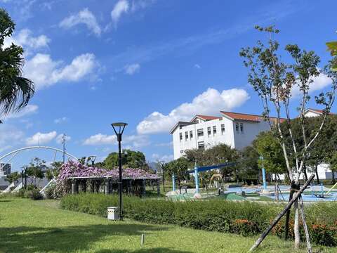 迪化休閒運動公園的綠地藍天與遠方的跨堤景觀平臺(圖片來源：臺北市政府工務局衛生下水道工程處)