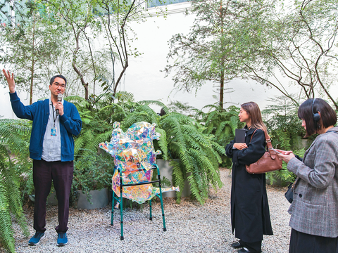 策展人穆柏安(左)於美術館中庭花園導覽作品《心.坎》。