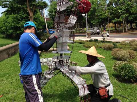 公園處員工在豔陽下為運動綠雕進行現場定位及固定工作。（圖／台北市工務局公園路燈工程管理處提供）