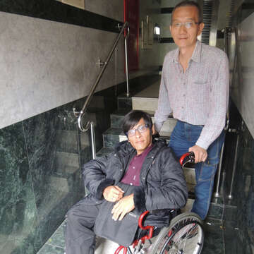 環保局同事每天下樓幫忙將張忠仁的輪椅抬上階梯，讓他能順利進入辦公室辦公。（攝影／Kuan）