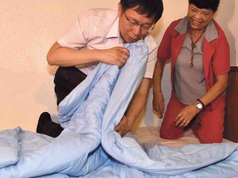 何仙姑さん（右）に布団の畳み方術を学ぶ柯文哲台北市長（左）