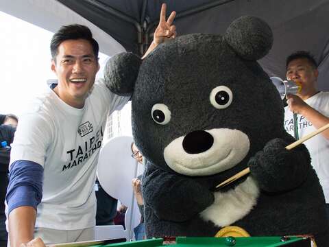 熊讚與旅美棒球好手陳偉殷在臺北馬拉松現場攤位一同較勁撞球。（吳朋玲攝）