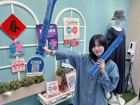 民眾手持加油棒於特約店家拍照，熱情為選手應援(圖片來源：臺北市商業處)