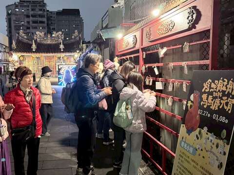 民眾在「燈照艋舺:馬馬慶元宵」活動許願牆綁上許願卡,祈求平安與心願成真。(圖片來源:臺北市政府觀光傳播局)