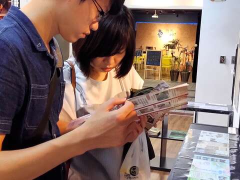 民眾於特展現場翻閱文宣品及旅遊導覽手冊