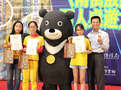 〈南街殷賑〉百人桌遊大賽由吳興國小603班同學奪冠，冠軍同學開心地與熊讚合照。