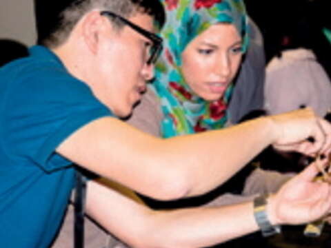 設計師周育潤（左）教導杜拜學員竹編球技巧展。