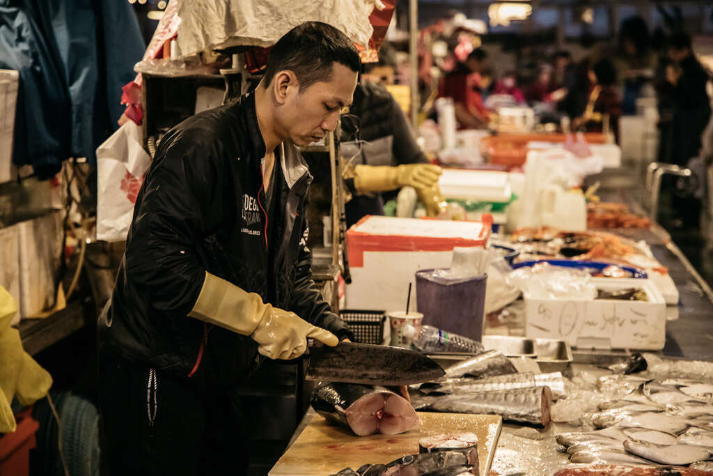 用專注的神情和熟練的刀法分切鮮魚，是魚市場的日常風景。