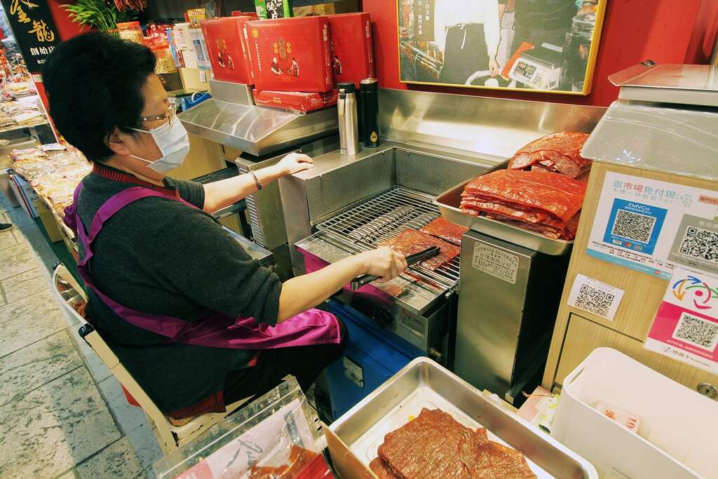 金龍肉乾創始店老闆娘白玉嬌半世紀以來堅守崗位，在攤位前為客人烤出一片片令人驚艷的好吃肉乾