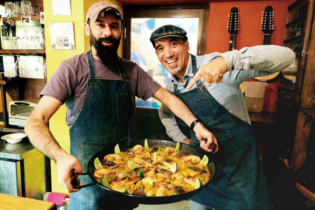 「樂盒子」兩位老闆路冰（左）和若森與他們的招牌菜「Paella西班牙海鮮燉飯」。（攝影／謝三泰）