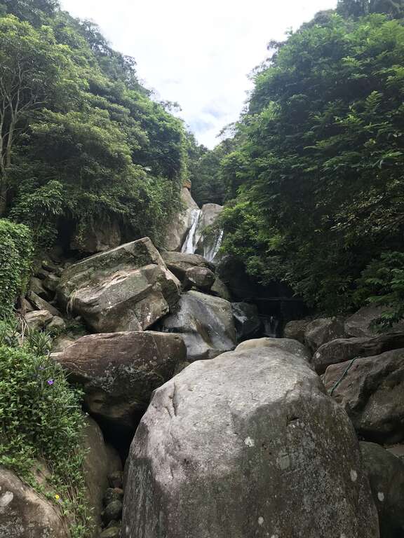 圆觉瀑布两道水流从大岩壁上倾泻而下下方堆积许多大岩块民众喜爱在旁打坐