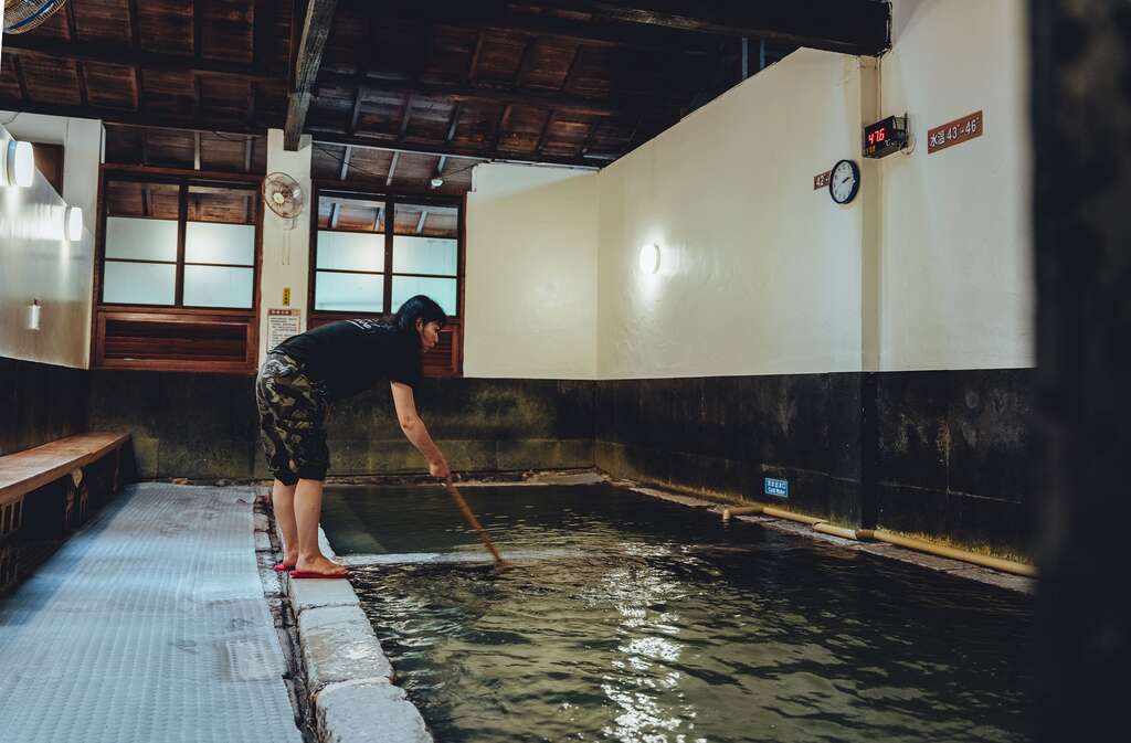 温泉服务人员使用竹棒混和温泉与冷水，让整池水温达到均衡。（摄影／张晋瑞）