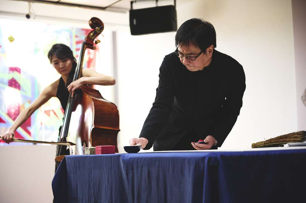 知名书法家暨诗人许悔之使用稻秆现场挥毫，并由国家交响乐团低音提琴手蔡歆婕(图左)伴奏。