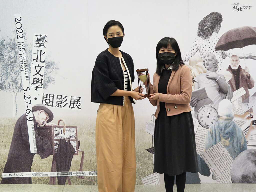 【0504台北文学．阅影展记者会】文化局副局长陈誉馨递沙漏给影展嘉宾桂纶镁，象徵影展主题时间的记忆