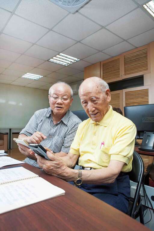 裴尚德爷爷（右）最喜欢下课後和朋友一起练习滑手机。（李庭欢摄）