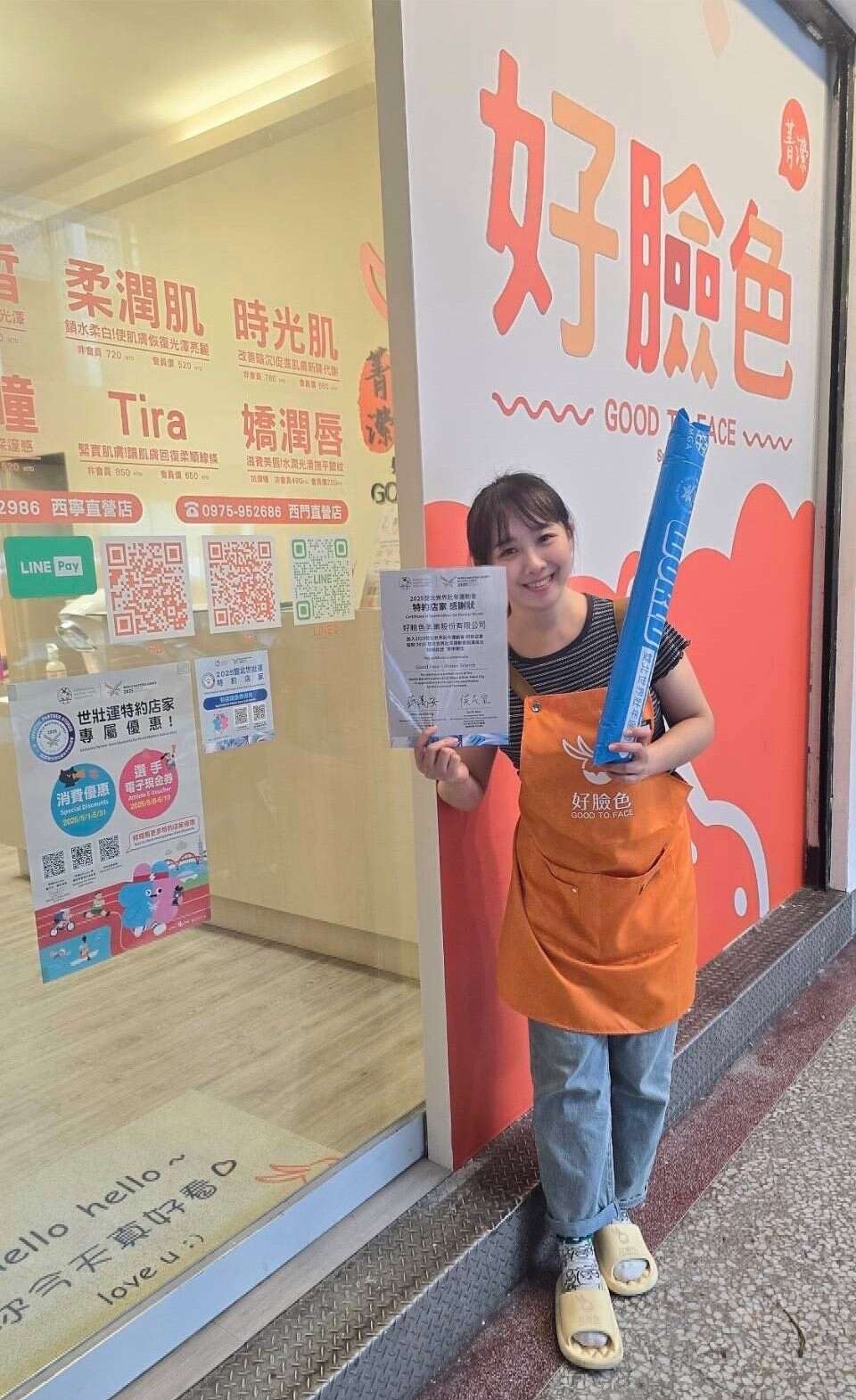 店员手持加油棒与活动文宣热情合影，力挺世壮运、欢迎大家来消费(图片来源：台北市商业处)
