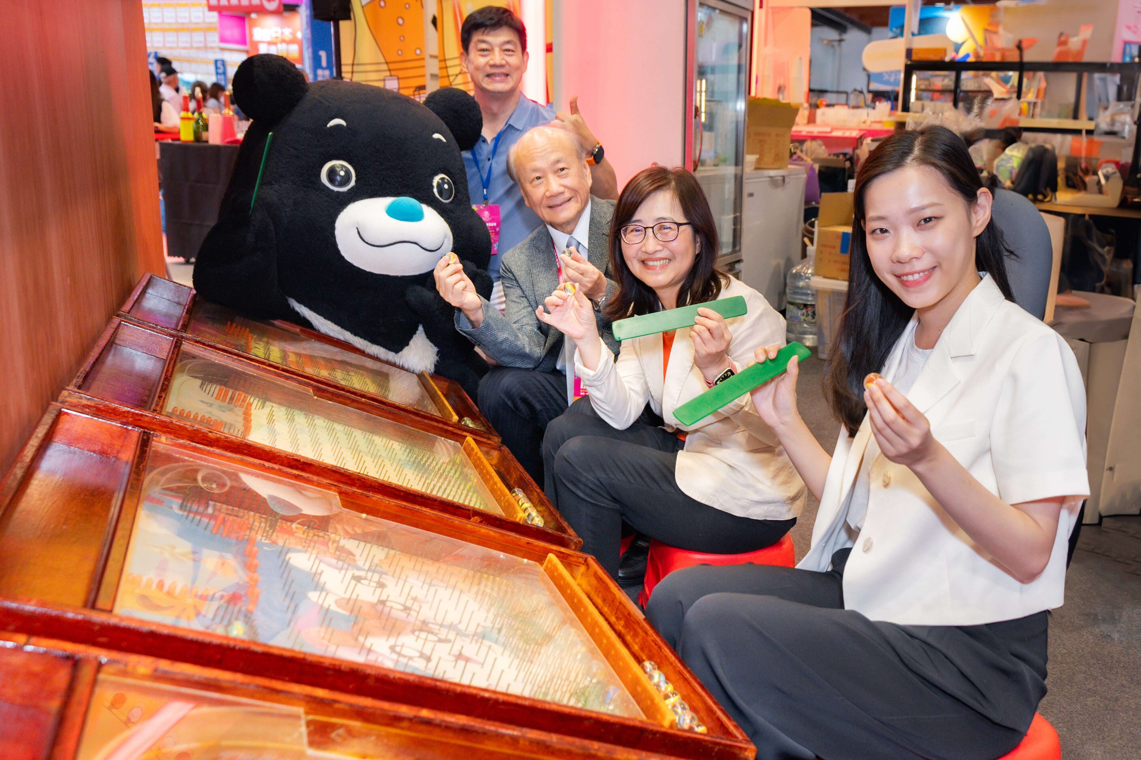 台北市林奕华副市长（中）、观传局余祥局长（右）与台湾旅游交流协会张家祝理事长（左），体验「台北馆」复古夜市手拨弹珠游戏。