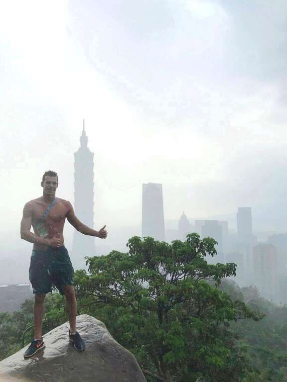 匈牙利游泳選手冒著細雨登象山，興奮地脫去上衣與臺北101合影留念。
