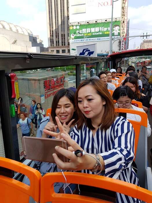 一上觀光巴士就忍不住拍照的泰國部落客，迫不及待要將美麗的臺北介紹給網友。