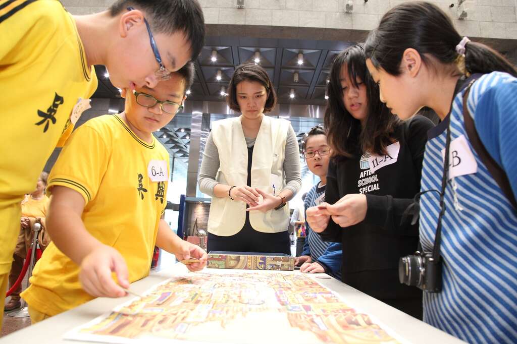 参赛学生们聚精会神，仔细寻找〈南街殷赈〉画布中的招牌、建筑、人物等位置。