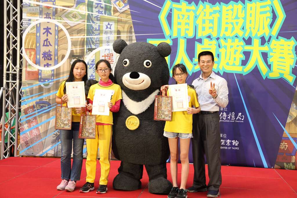 〈南街殷賑〉百人桌遊大賽由吳興國小603班同學奪冠，冠軍同學開心地與熊讚合照。